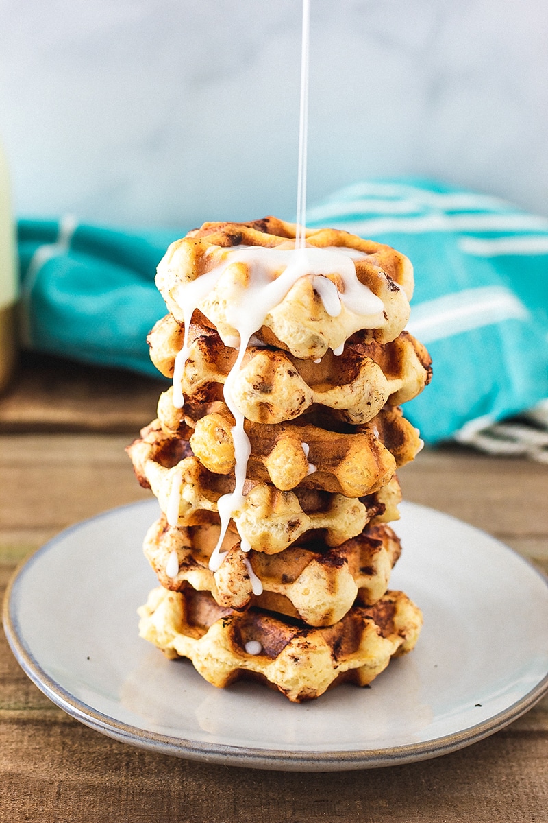 Stack of cinnamon rolls with icing being poured on top